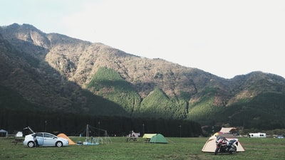 白天，在白云下的群山附近有各种颜色的圆顶帐篷